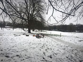 Bare trees on snow field against sky during winter