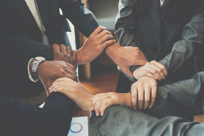 Midsection of business people stacking hands