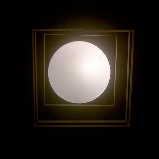 indoors, low angle view, circle, geometric shape, window, built structure, architecture, illuminated, dark, glass - material, shape, directly below, copy space, sky, no people, night, lighting equipment, electricity, ceiling, home interior