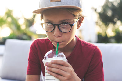 Boy sitting on bench while drinking milkshake