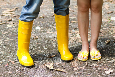 Low section of child standing on yellow shoes