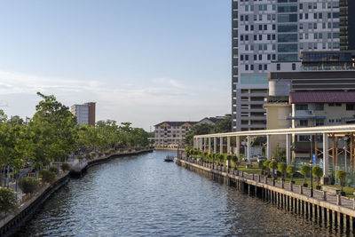 Bridge over river by buildings in city against sky