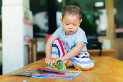 Boy with book on table at home