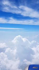 Low angle view of airplane wing over clouds