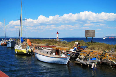 Sailboats moored in sea against sky