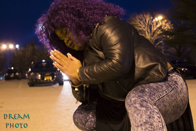 Woman sitting on illuminated street at night