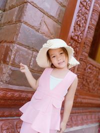 Portrait of smiling girl standing against built structure