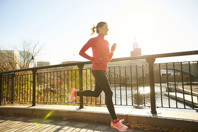 A woman running across a bridge in an urban park.