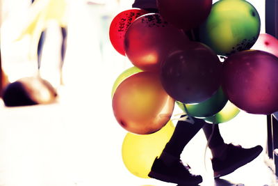 Low section of person with multi colored balloons walking on floor