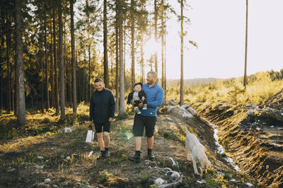 Parents with son and pet dog walking in forest