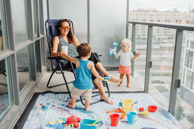 Young mother spending time together with children babies on balcony at home. staycation 