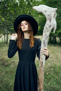 Portrait of young woman standing against trees