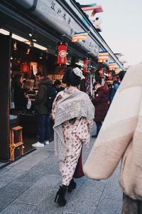 Rear view of people walking on street in city