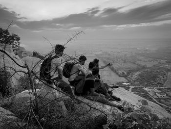 People sitting on shore against sky
