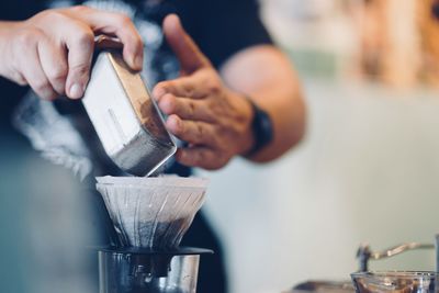 Midsection of person preparing coffee in cafe