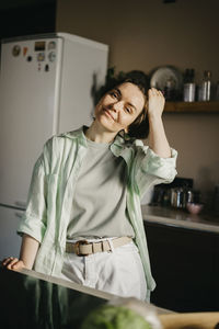 Smiling woman with hand in hair at kitchen