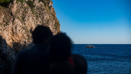 Rear view of people in sea against clear blue sky