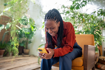 Side view of young man using mobile phone while sitting outdoors