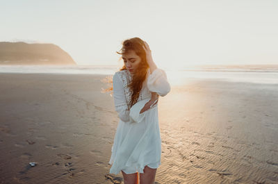 Young lady beautiful sandy beach sunset magic hour white dress 