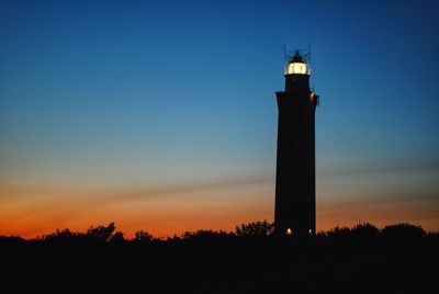 Silhouette lighthouse against sky during sunset