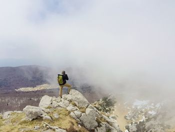 Man on horse standing on mountain against sky