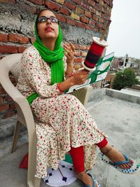 Full length of mid adult woman holding kite and thread while sitting on chair