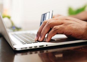 Cropped hands of woman using laptop