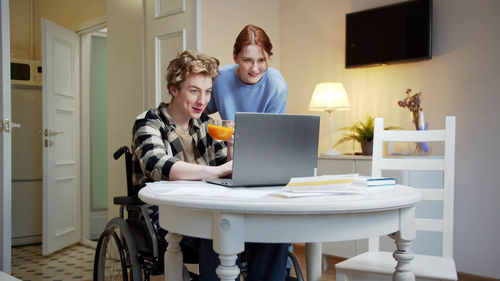 Smiling young couple sitting by desk at home