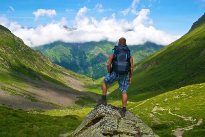 Rear view of man standing on rock against mountain