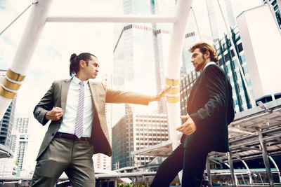 Low angle view of businessmen fighting while standing outdoors
