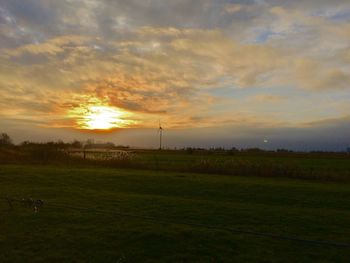 Scenic view of grassy field against sky during sunset