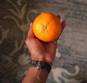 Cropped hand holding orange indoors