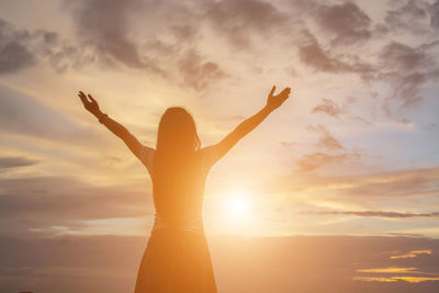 Low angle view of woman standing against sky during sunset