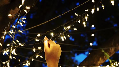 Close-up of illuminated christmas lights against sky at night