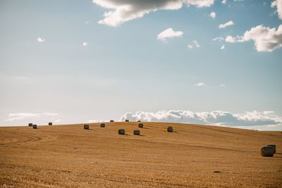 Hay bales on field against sky