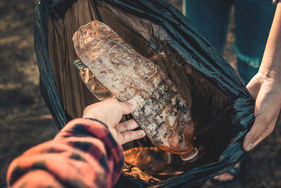 High angle view of man throwing dirty plastic bottle in trash bag