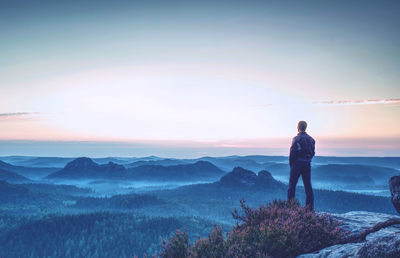 Hiker enjoys valley view from hilly viewpoint. hiker reached top of mountain and watching sunset