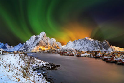 Scenic view of lake by snowcapped mountains against sky at night