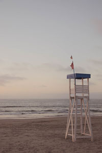 Lifeguard hut on beach against sky during sunset