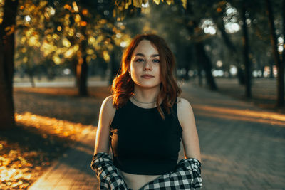 Portrait of young woman standing against trees