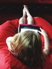 Rear view of woman using digital tablet while sitting on bean bag