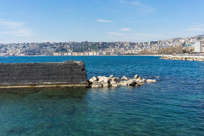 Scenic view of sea by buildings against sky