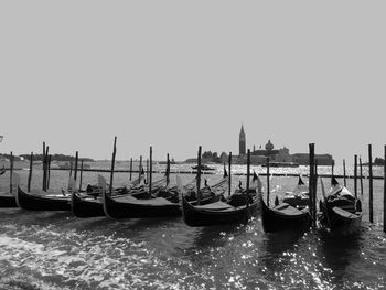 Traditional gondolas moored by wooden post in sea against clear sky