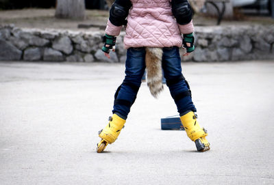 Low section of woman skateboarding on road