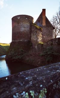 Old building by river against sky