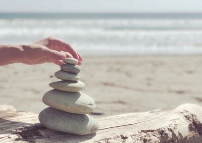 Cropped image of hand stacking pebbles at beach