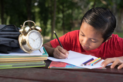 Boy studying on table in park
