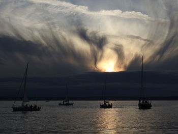 Sailboats sailing on sea against sky during sunset