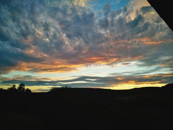 Silhouette landscape against dramatic sky during sunset