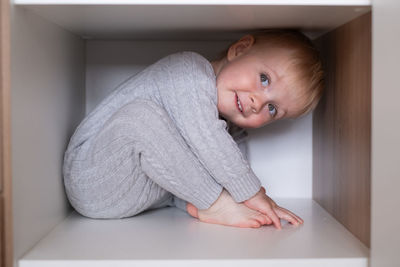 Portrait of cute baby boy sitting on floor at home